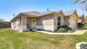 A two-story house with a brick facade, a front porch, and a well-maintained lawn. - Shop, Dine & Unwind: Pet-friendly Home in Austin! (Austin)