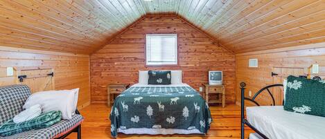 A cozy attic bedroom with a sloped ceiling, a bed with a forest-themed bedspread, a sofa with a checkered cover, and a small window.