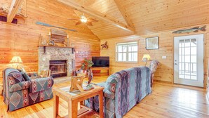 Ein Blockhaushaus-Interieur mit Kamin, zwei Sofas, einem Fernseher und Holzdielen.