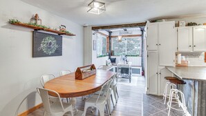 Una cocina moderna con armarios blancos, una mesa de comedor de madera y vistas al exterior.