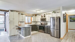 Una cocina moderna con armarios blancos, electrodomésticos de acero inoxidable y una isla grande con taburetes.