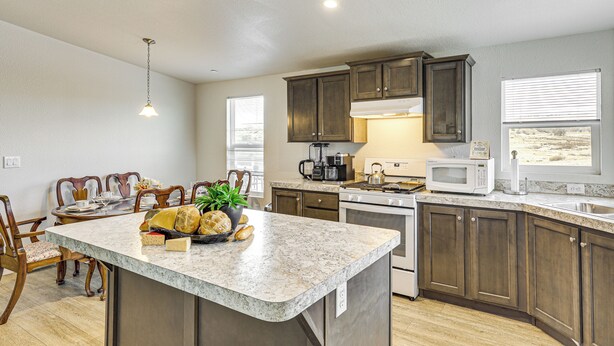 A kitchen with a marble countertop, wooden cabinets, a built-in oven, and a dining area with chairs and a table. - Near Ramona Wineries: Mtn-view Haven w/ Large Yard (Ramona)