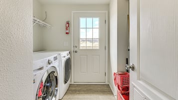 A laundry room with a washing machine, dryer, and a fire extinguisher on the wall.