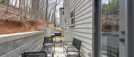 Un patio con dos sillas y una mesa, un muro de contención de concreto y una terraza de madera.