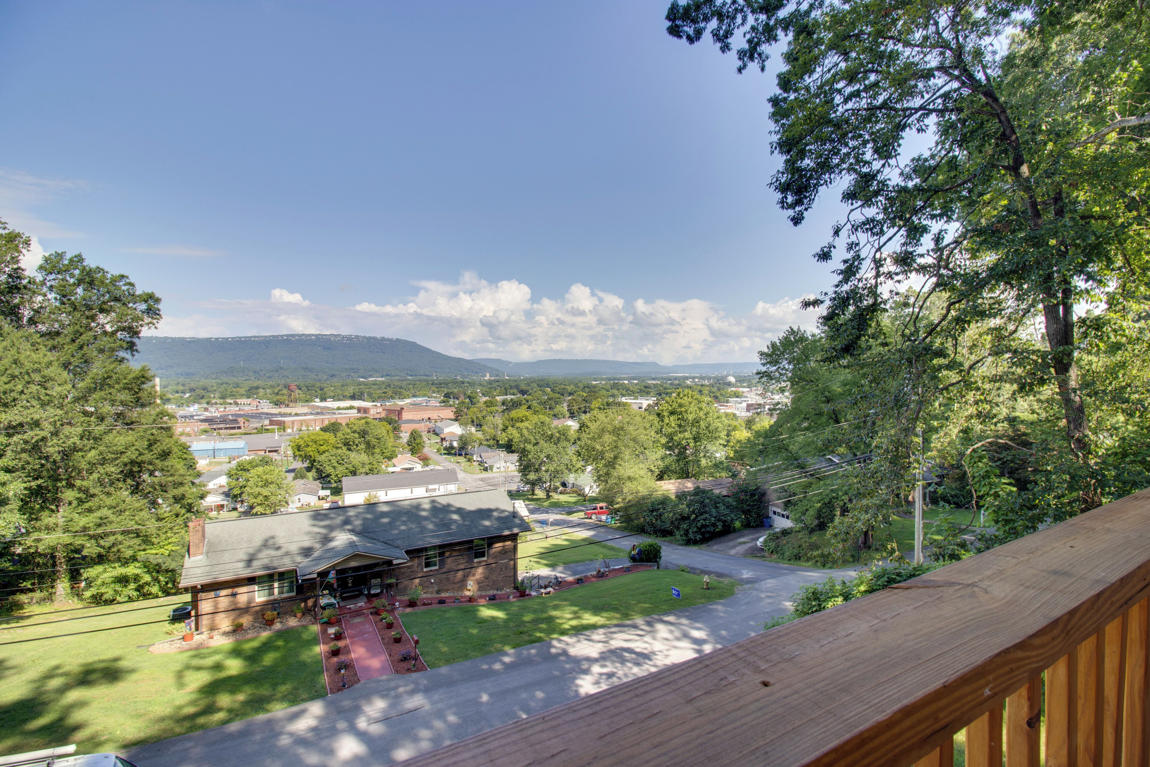 A residential area with a house, a driveway, and a view of a distant town and mountains.