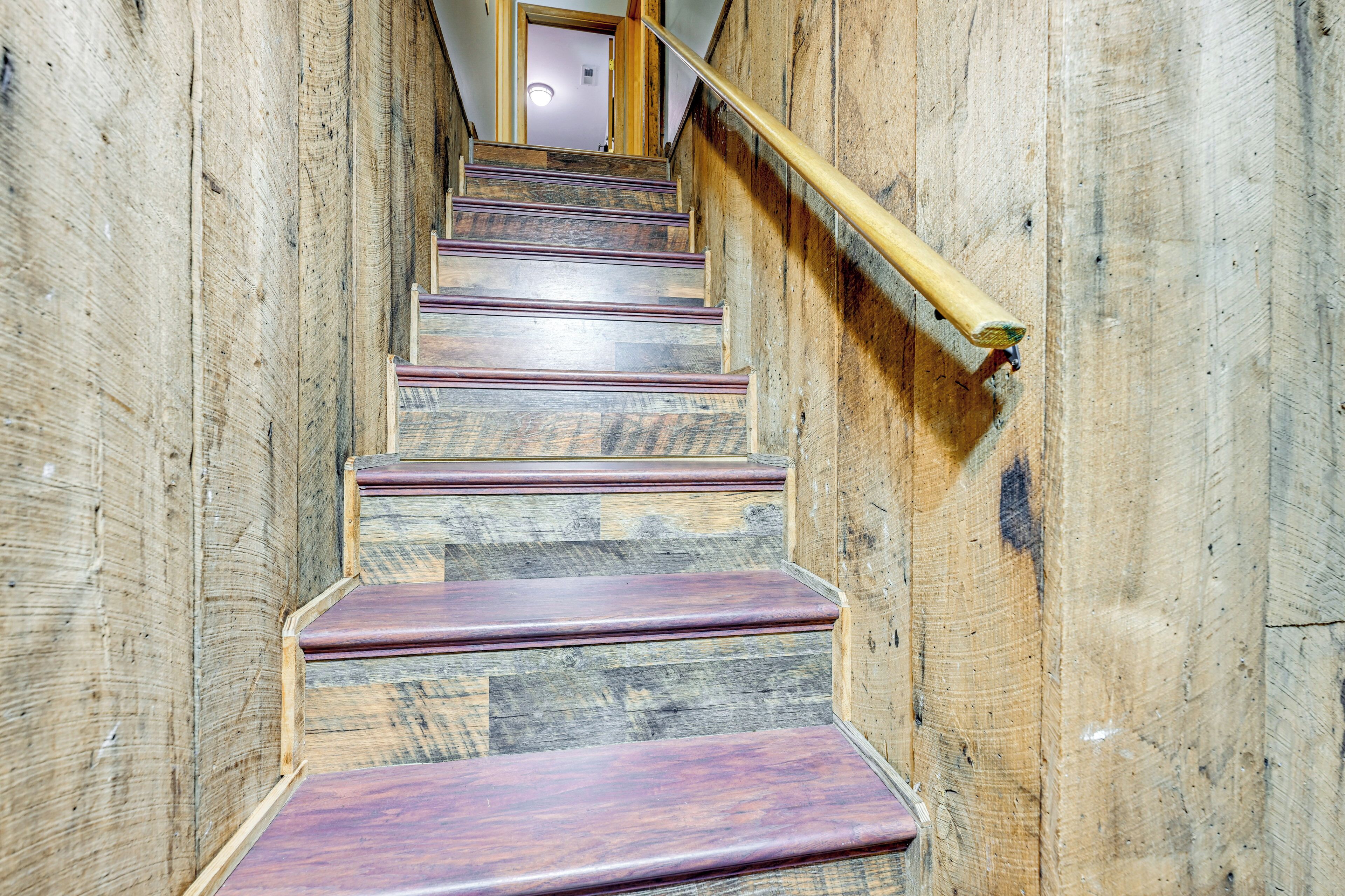 A wooden staircase with a handrail, leading to an interior space.