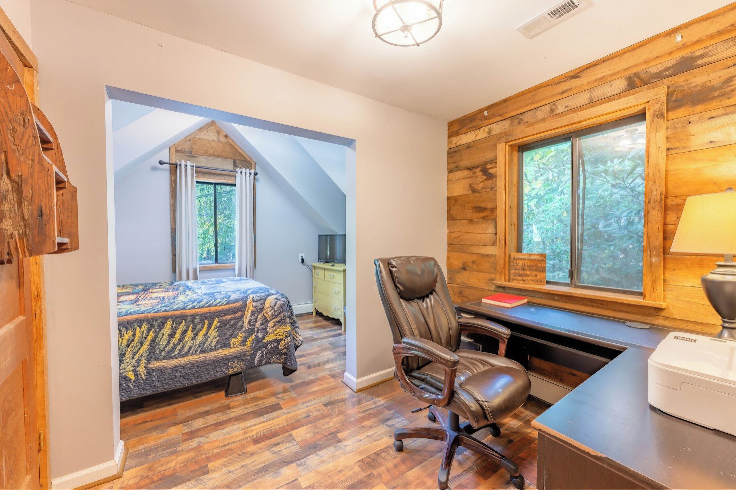 A bedroom with a bed, a desk, a chair, and a window.