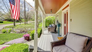 A porch with a wicker chair, a flag, and a view of a street. - Walk to Main St & Parks: Zionsville Village Home (Zionsville)