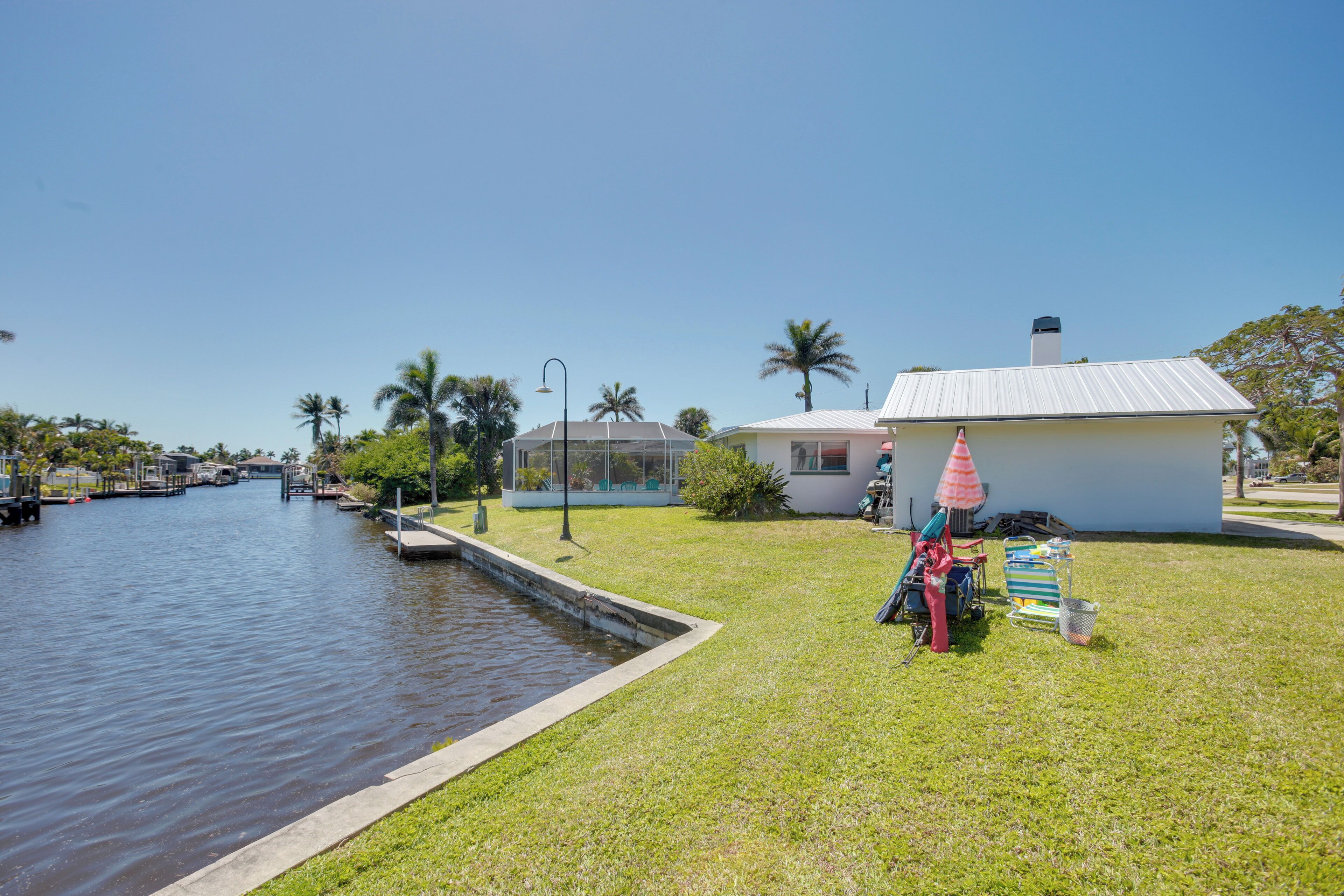 A waterfront property with a grassy lawn, a small house, and a dock.