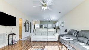A spacious living room with a large white leather sofa, a grey leather sectional, and a flat-screen TV mounted on the wall. - 6 Mi to Myrtle Beach Hot Spots: Cozy Condo! (Socastee)