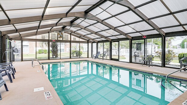 A covered swimming pool with clear glass walls, a tiled floor, and a few chairs around the pool. - 6 Mi to Myrtle Beach Hot Spots: Cozy Condo! (Socastee)