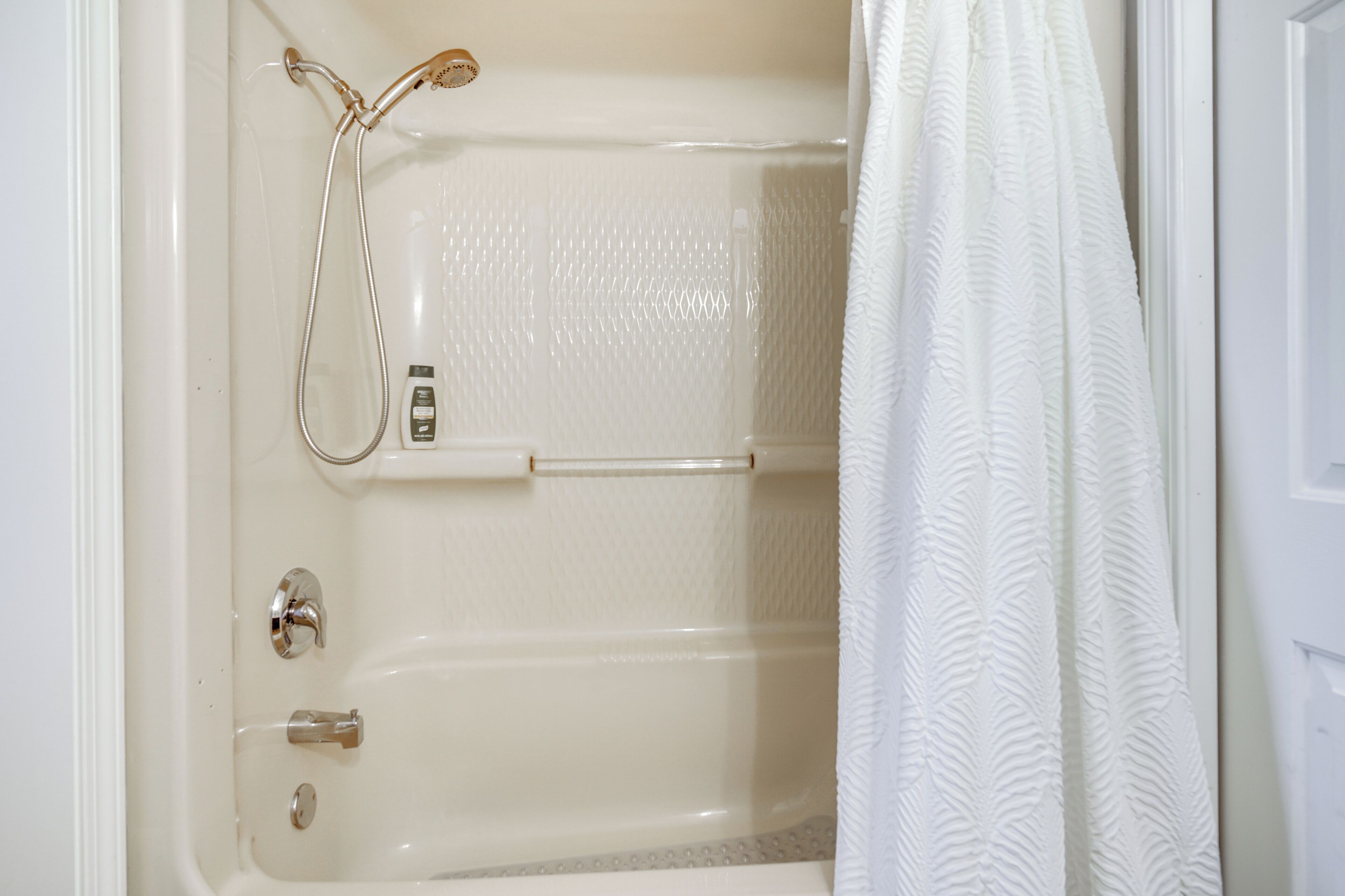 Une baignoire équipée d’un pommeau de douche à main, d’un panneau de commande et d’un porte-serviettes.