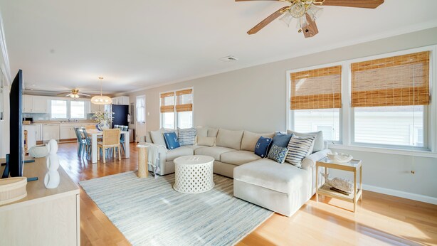A spacious living room with a large white sofa, a coffee table, and a dining area with a table and chairs. - Walk to Brigantine Beach: Home w/ BBQ & Yard (Brigantine)