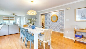 A dining area with a white table and blue chairs, a ceiling fan, and a decorative mirror on the wall. - Walk to Brigantine Beach: Home w/ BBQ & Yard (Brigantine)
