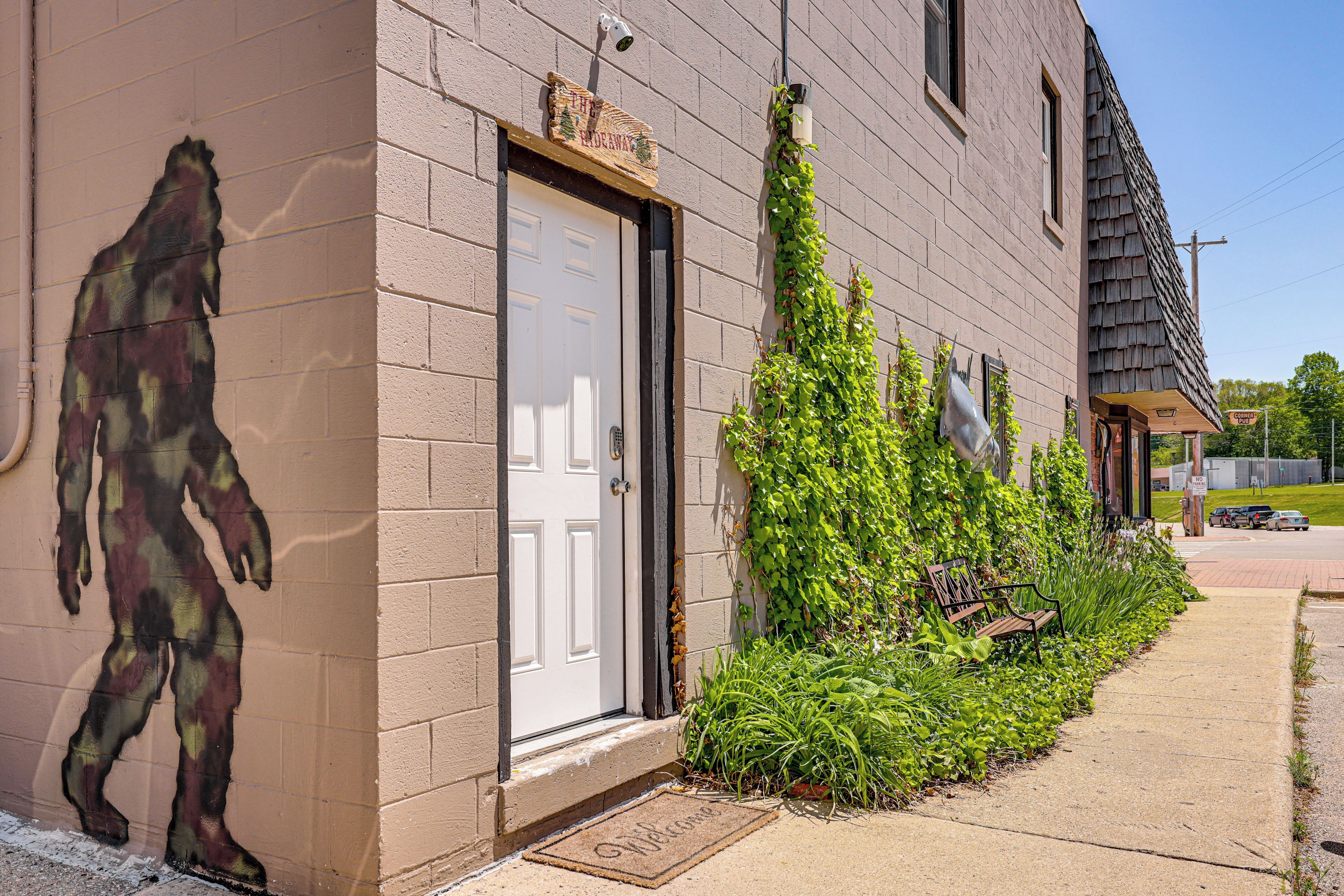 A building with a white door, a welcome mat, and a bench outside.
