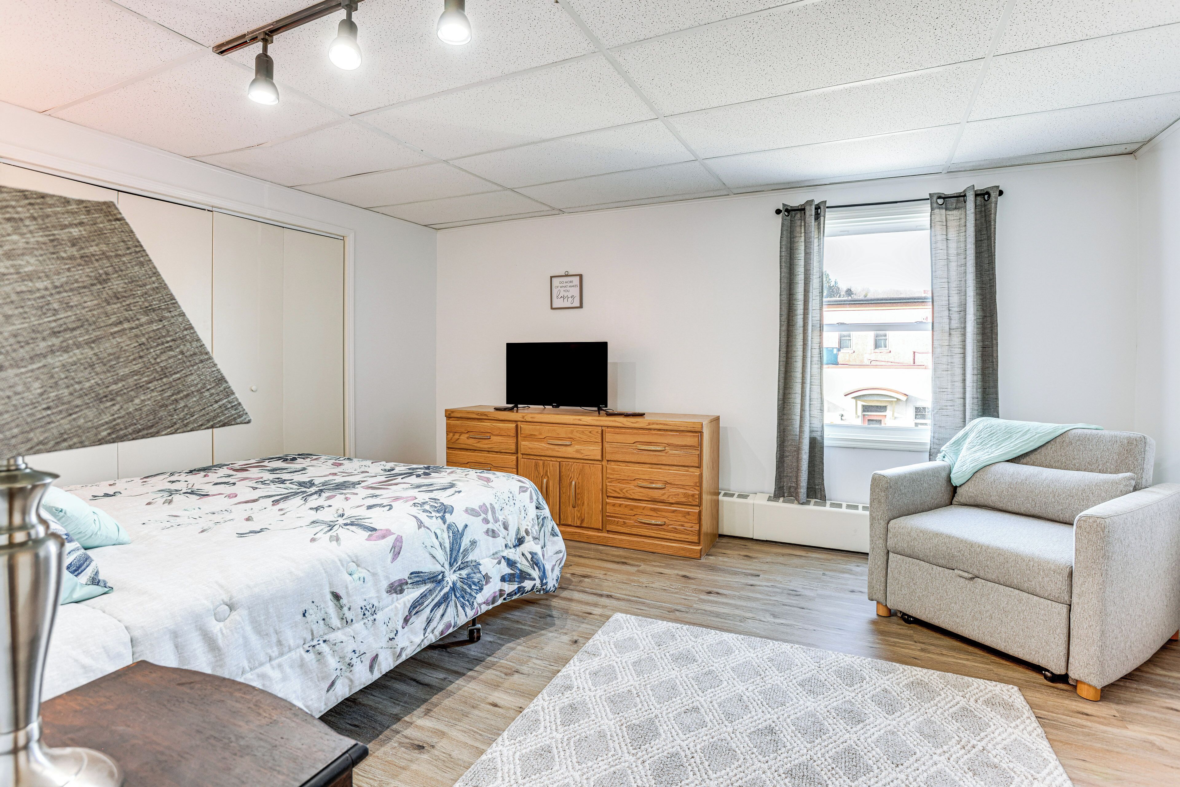 A bedroom with a bed, a dresser, a chair, and a television.