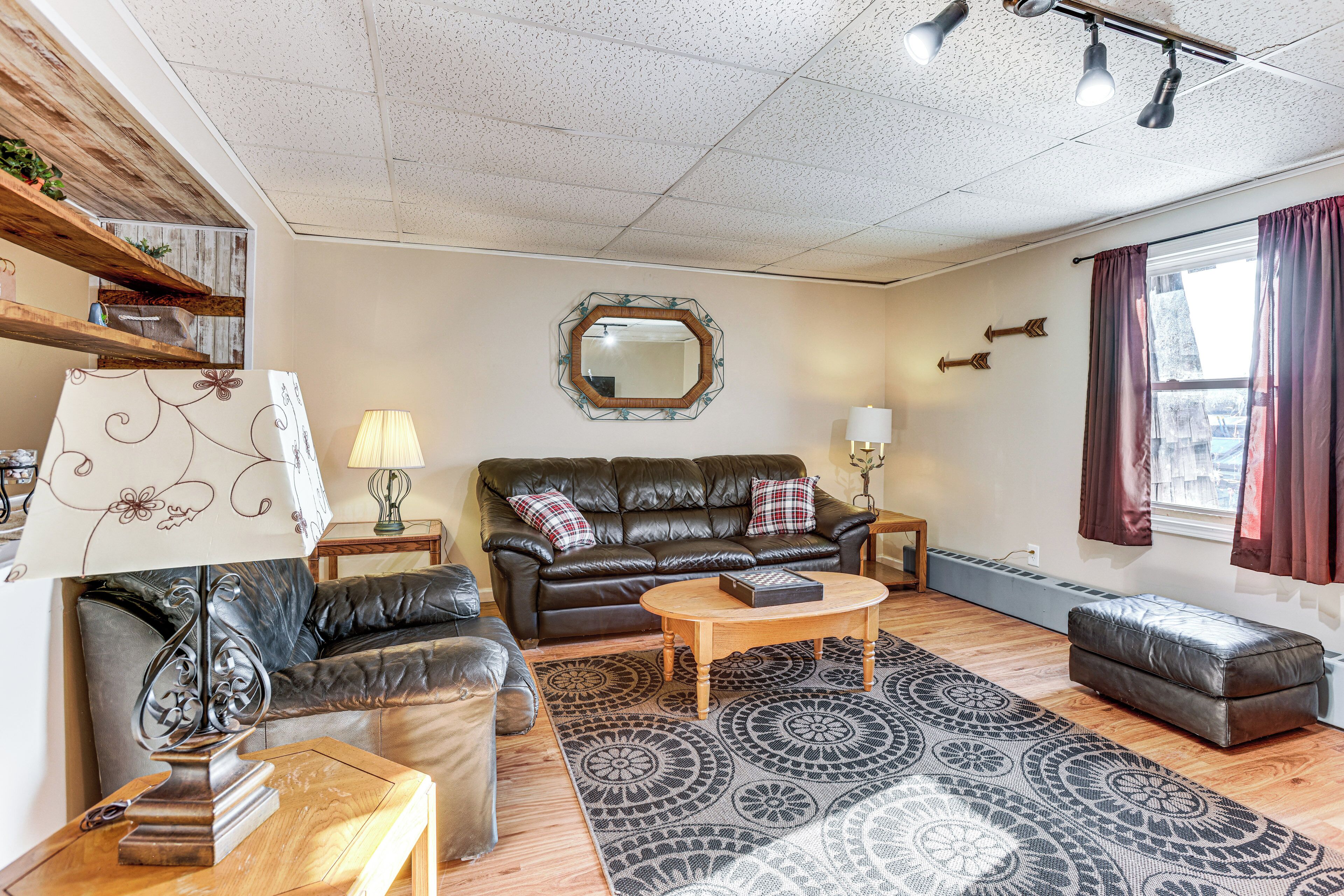 A living room with a leather sofa, a coffee table, a patterned rug, and a mirror on the wall.