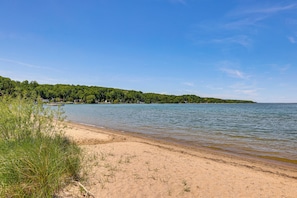 A beach with clear water, a sandy shore, and a forested island in the distance. - Downtown Beulah Pet-friendly Apt Near Lake & Shops (Beulah)