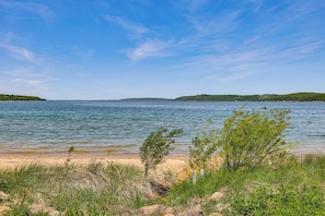 A beach with clear water, grassy areas, and distant hills. - Downtown Beulah Pet-friendly Apt Near Lake & Shops (Beulah)