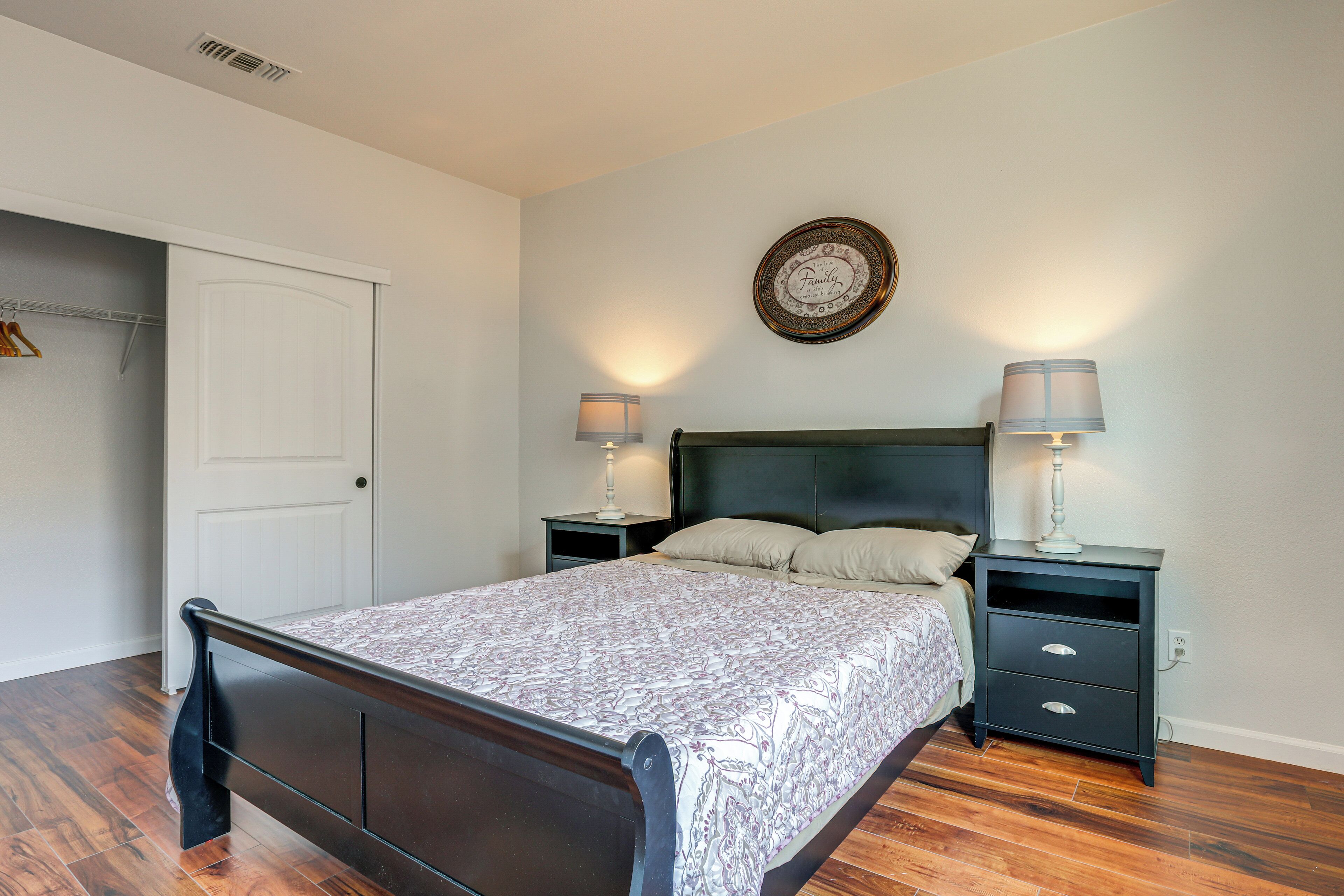 A bedroom with a bed, two nightstands, a wall clock, and a door.