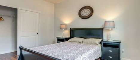 A bedroom with a bed, two nightstands, a wall clock, and a door.