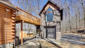 Une cabane en rondins avec une terrasse en bois, une entrée en pierre et une grande fenêtre.