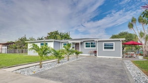 A two-story house with a driveway, a lawn, and a patio area with a red umbrella. - 2 Mi to Hard Rock Stadium: Studio in Miami Gardens (Miami Gardens)