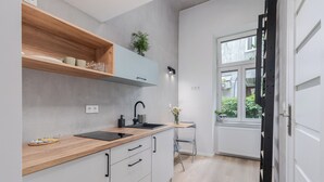 Una cucina moderna con scaffali in legno, un lavandino nero e una finestra che si affaccia sul verde.