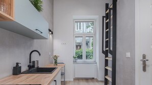 Una cucina moderna con piano di lavoro in legno, lavello nero e piano cottura integrato. Si vede una finestra con vista sul verde.