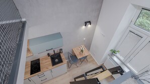 Una cucina compatta con piano cottura integrato, lavello e un piccolo angolo ristoro con tavolo e sedie.