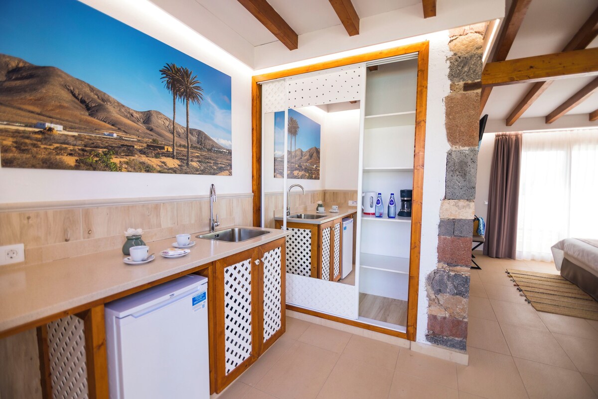 A compact kitchen with a wooden countertop, a built-in sink, and a refrigerator.