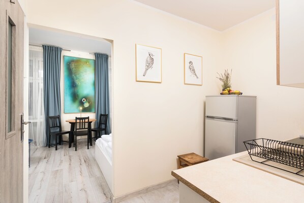 Habitación de hotel compacta con comedor, pequeña cocina y vistas al exterior.