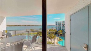 A balcony with a pool view, a table with chairs, and a door.