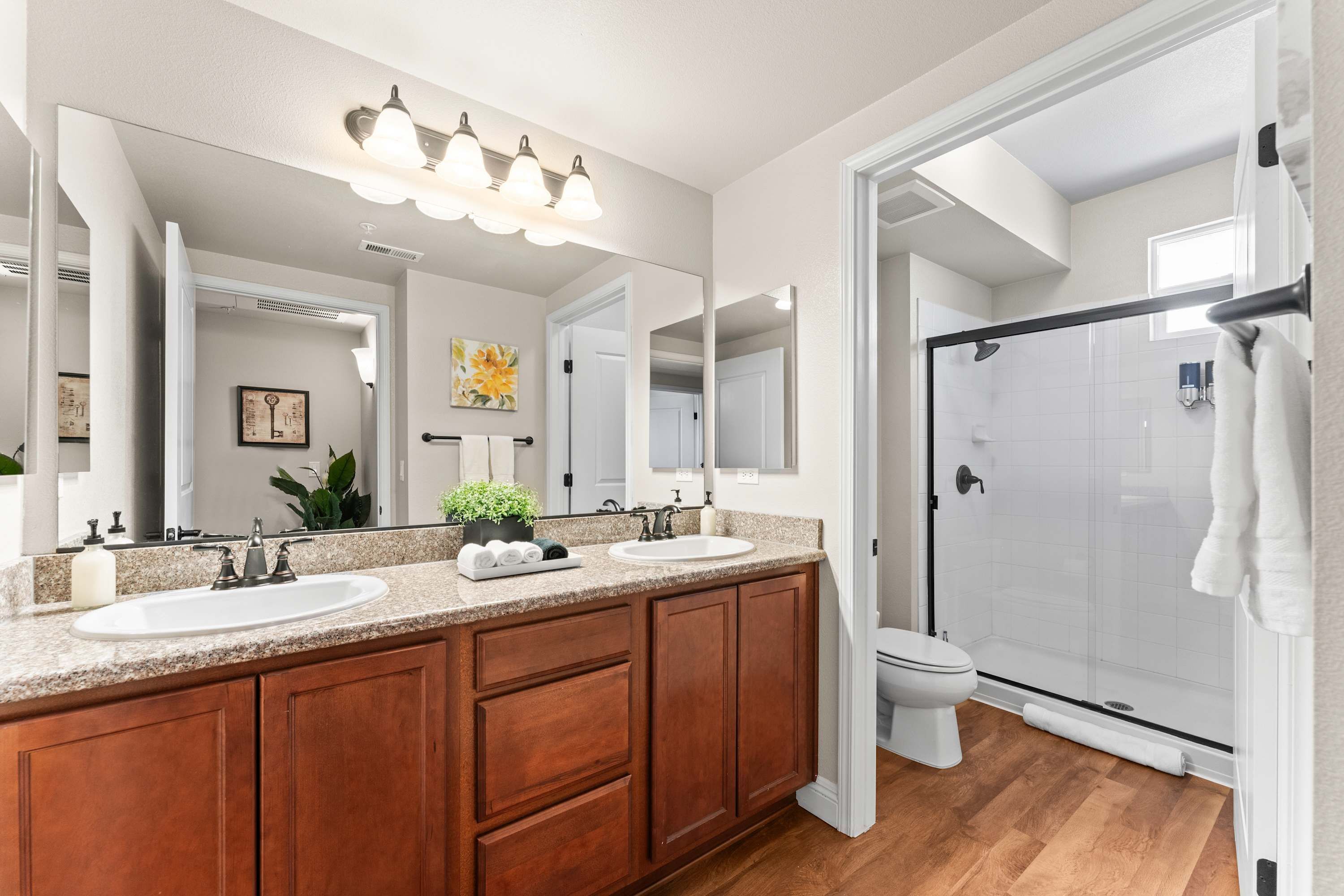 A modern bathroom with a double sink vanity, a large mirror, and a walk-in shower.