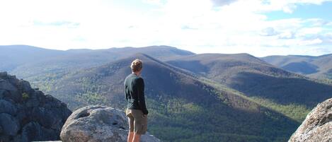 A person standing on a rock overlooking a mountainous landscape.