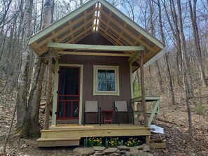 A cabin with a wooden deck, two chairs, a red door, and a window. - Moonshine Glamping Cabin near Old Rag Mountain in Shenandoah National Park (Etlan)