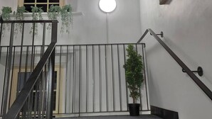 Una escalera con barandilla de metal, un candelabro redondo y plantas en macetas.