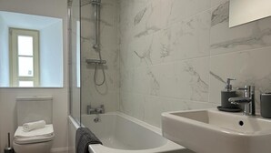 A modern bathroom with a shower, toilet, bathtub, and sink.