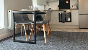 A modern kitchen with a dining table, chairs, and a built-in oven.