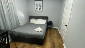 Een slaapkamer met een bed, nachtkastje en een klein bureau.