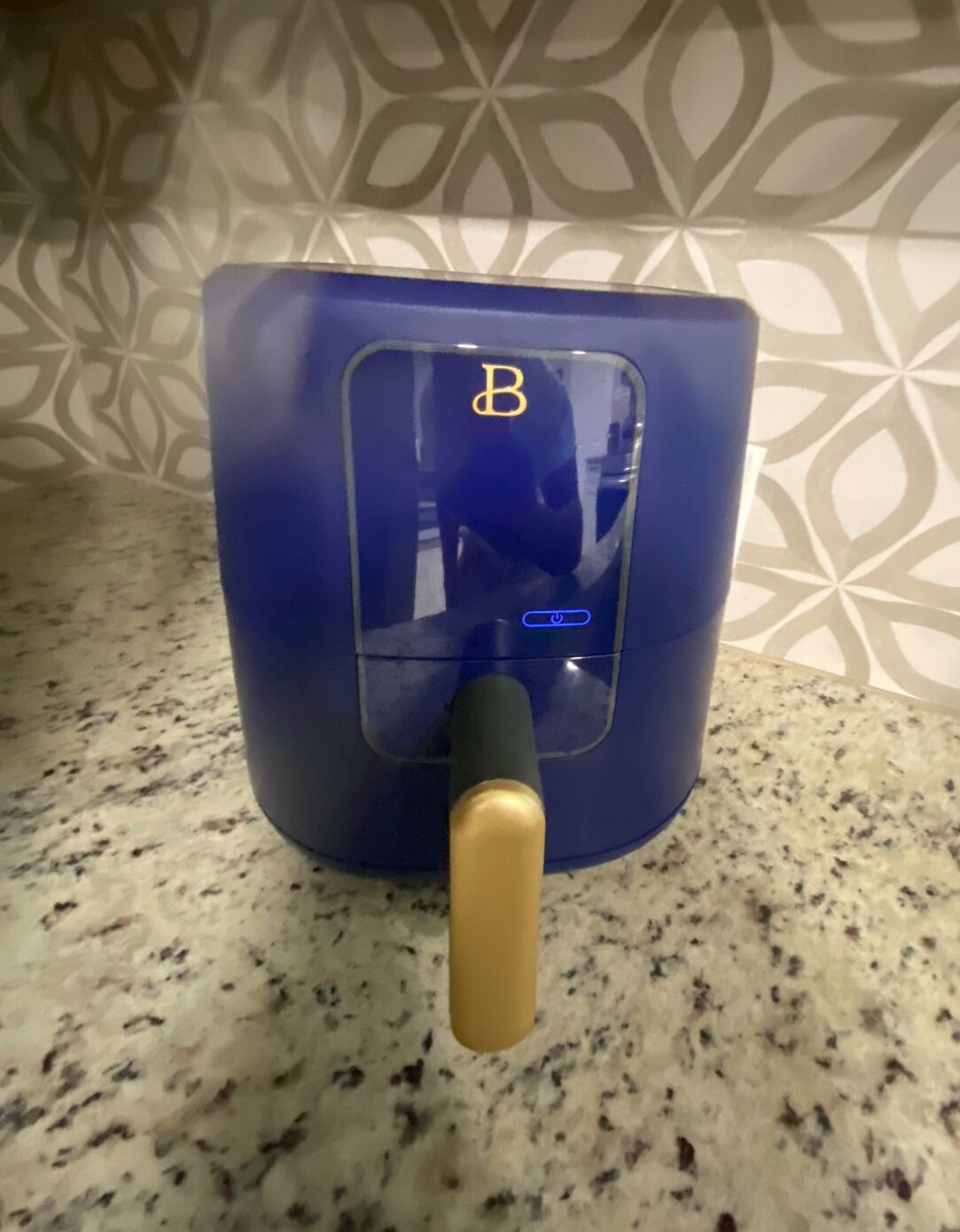 A blue appliance with a gold handle and a control panel with a 'B' symbol.
