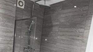 A modern bathroom with a glass-enclosed shower, a standalone bathtub, and grey marble tiles. - Seaside Escape Apartment in Southend-on-sea (Southend-on-Sea)