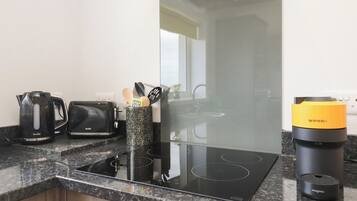 A kitchen with a black induction cooktop, a Breville toaster, a Nespresso coffee maker, and a Magimix appliance.
