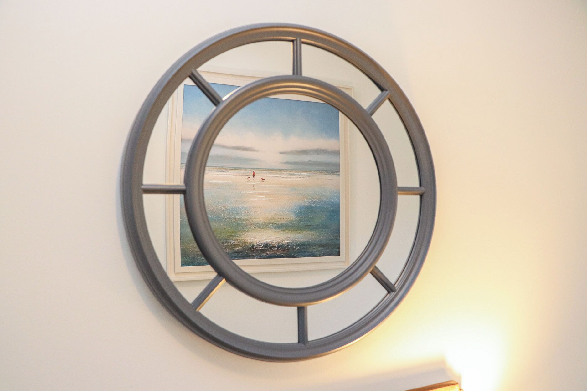 A framed picture of a beach scene with a circular window frame.