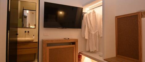 Un baño moderno con tocador de madera, televisor montado, perchero y espejo.