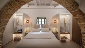 Ein Schlafzimmer mit einem großen Bett, zwei Nachttischen, einer Pendelleuchte und einem Steingewölbe.