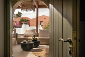 Relax in this open-plan living area with a sofa set, coffee table, and dining table, offering a view of the landscaped garden.