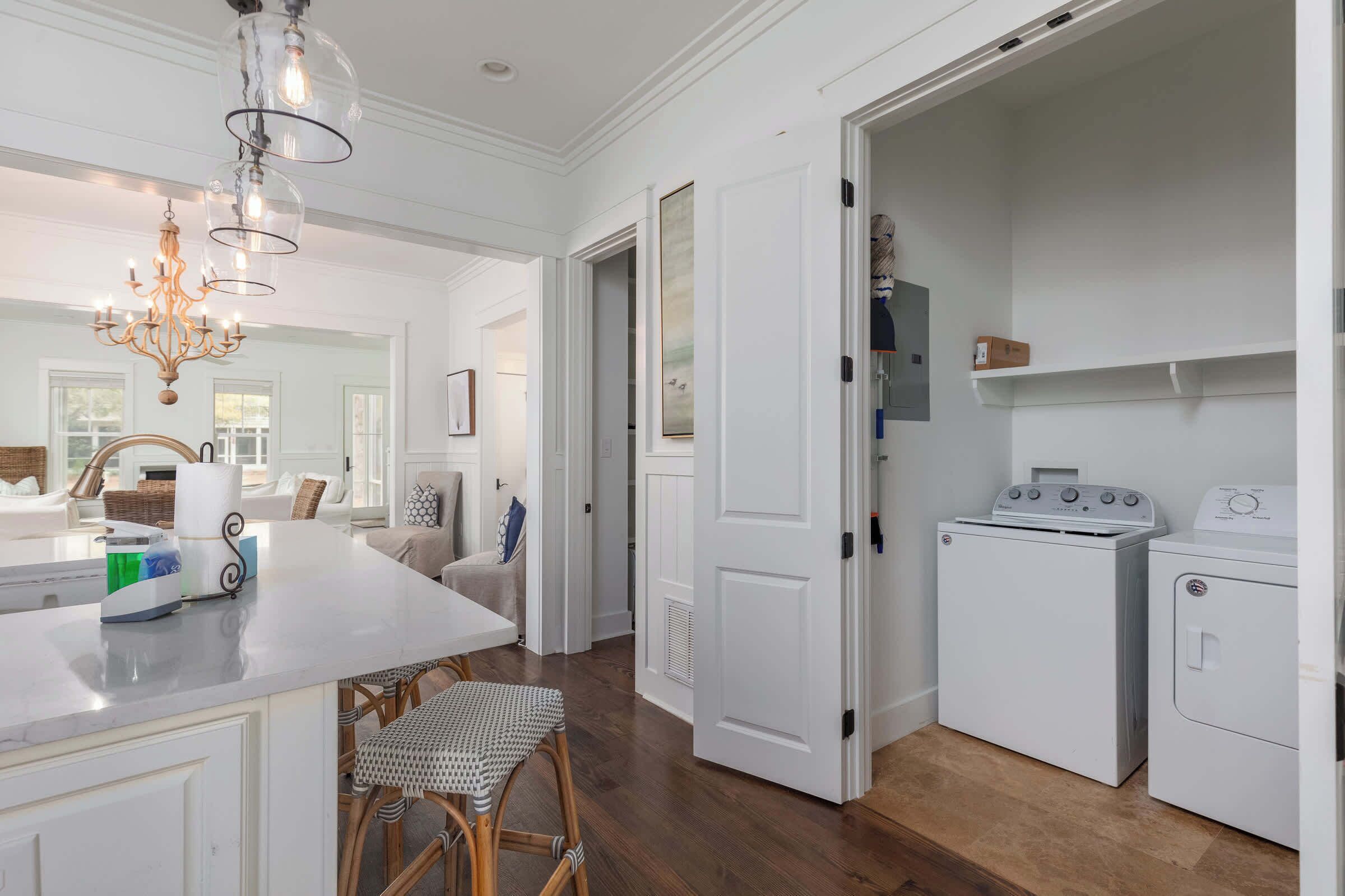 A kitchen with a marble countertop, a chandelier, and a washing machine.