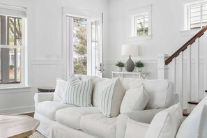 A white living room with a sofa, a lamp, and a staircase.