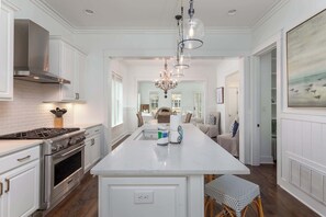 A kitchen with white cabinetry, a central island, stainless steel appliances, and a chandelier.